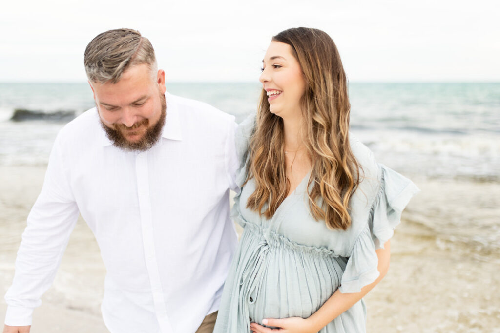 pensacola beach maternity photographer blue gown walking couple laughing
